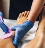 Waxing - Beautician Removing Unwanted Hair from Female Leg with Wax Strips in a Beauty Salon