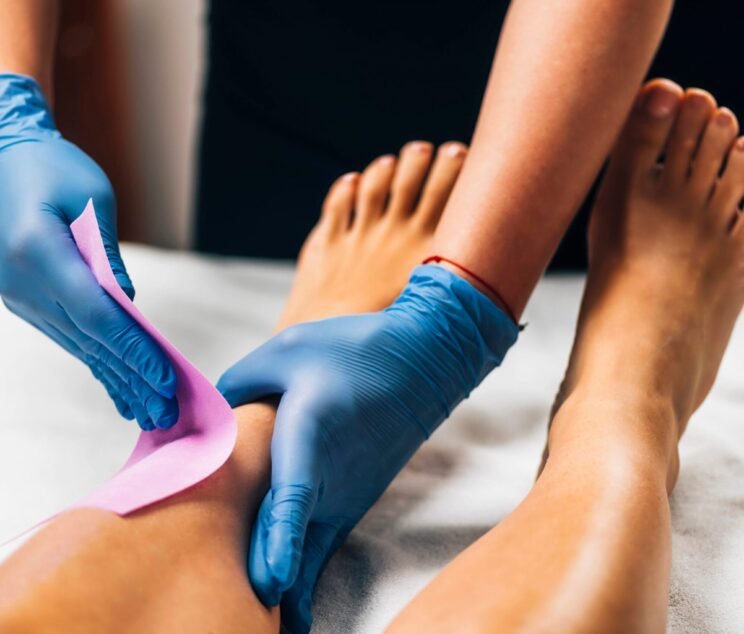 Waxing - Beautician Removing Unwanted Hair from Female Leg with Wax Strips in a Beauty Salon