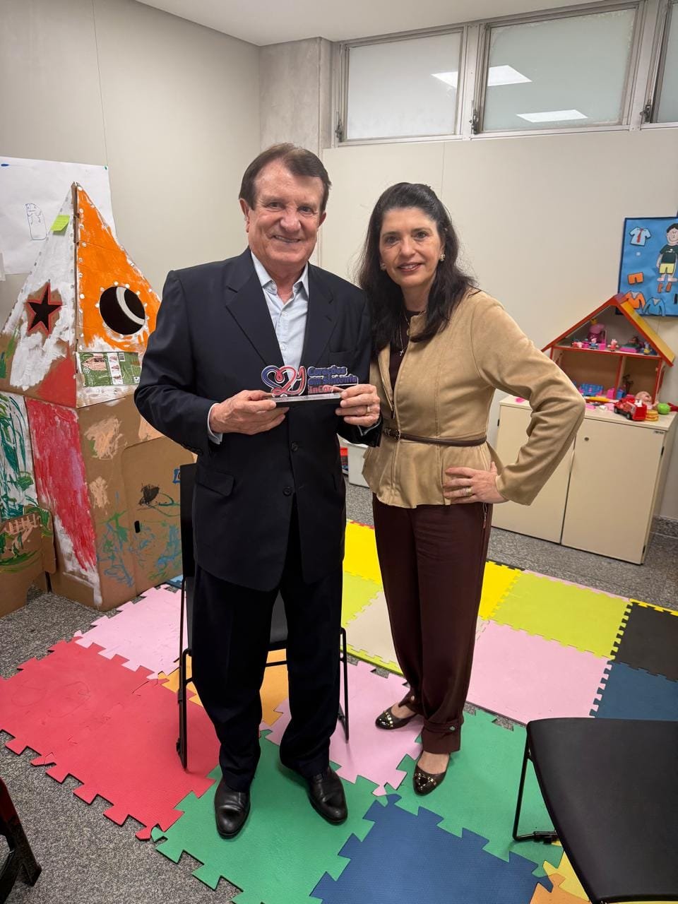 Estenio Campelo recebendo a placa da coordenadora do projeto, Dra. Claudia Kalil
